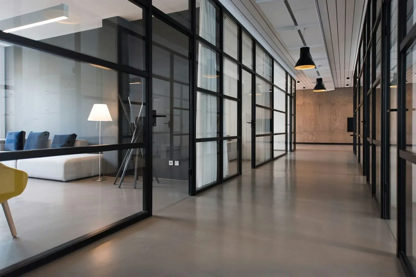 Glass-partitioned office corridor with a polished concrete floor